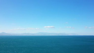 Yunanistan 'ın Corinth kenti yakınlarında berrak bir gökyüzünün altında, uzak dağları ve kıyı şeridini gören derin mavi deniz manzarası. Sakin deniz manzarası seyahat ve doğa kavramları için idealdir..