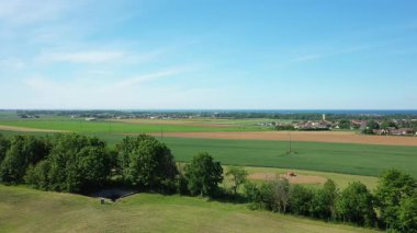 Fransa 'nın Normandiya kentindeki Battery Hillman yakınlarında açık mavi gökyüzünün altında küçük bir köy ve deniz bulunan yeşil tarlaların ve tarım arazilerinin geniş hava manzarası..