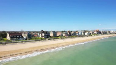 Kumlu Kılıç Sahili 'nin havadan görünüşü ve Lion sur Mer, Normandiya' daki sahil evleri, açık mavi bir gökyüzünün altında..