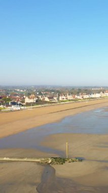 Lion-sur-Mer, Normandiya 'daki Kılıç Sahili' nde açık mavi gökyüzünün altında geniş kumlu sahil ve kıyı kasabası. Sahil boyunca geleneksel Fransız evleriyle sakin deniz manzarası.