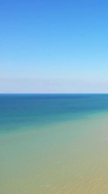 Bernieres-sur-Mer, Normandiya 'daki Juno Sahili' nde sakin, turkuaz sularla karşılaşan berrak mavi gökyüzünün sakin manzarası. Yumuşak dalgaları ve sakin atmosferi olan huzurlu deniz manzarası.