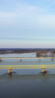 Fransa 'nın Sully-sur-Loire kentindeki Loire Nehri' ni geçen sarı bir köprünün geniş bir manzarası var. Nehir kıyısında kar ve başımızın üstünde sakin bir kış gökyüzü var..