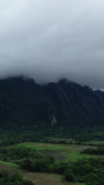 Dramatik sis, Vang Vieng, Laos yakınlarındaki yeşil dağları ve tarlaları kaplayarak sakin ve atmosferik kırsal bir manzara yaratıyor..