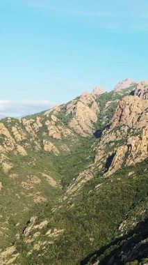 Scenic view of rugged mountains and lush green valleys under a clear blue sky in the Corsican countryside. Natural beauty and tranquility in a Mediterranean landscape.