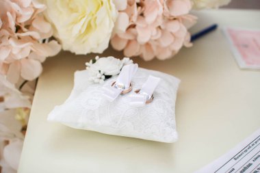 Altın alyanslar beyaz bir masada yatıyor.