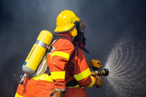 2 firemen use hydrant nozzle fighting with fire surround with da — Stock Photo, Image