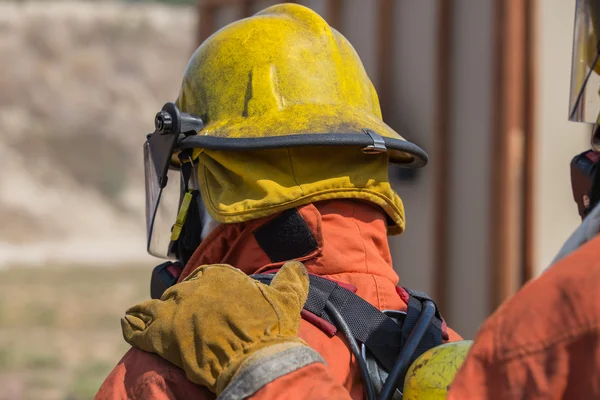 Mano de bombero puesta en el hombro del primer hombre para la señal en el trabajo en equipo de lucha contra el fuego — Foto de Stock