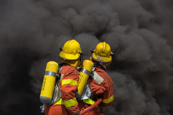 Dos bomberos en traje de extinción de incendios encuentro con fuego y negro — Foto de Stock