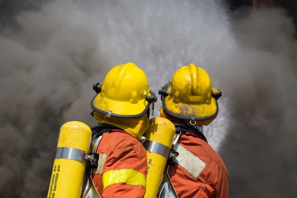 Two firefighter in fire fighting suit spray water to fire and bl — Stock Photo, Image