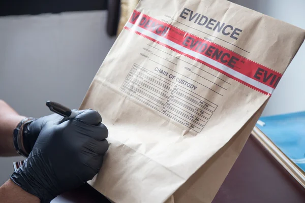 Hand in glove writing on evidence bag and seal by red tape in cr — Stock Photo, Image