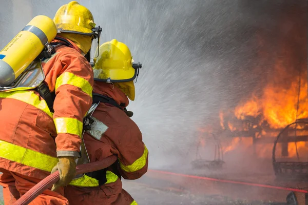 2 Feuerwehrleute versprühen bei Löscheinsatz Wasser — Stockfoto