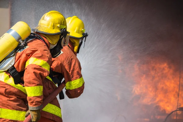 2 firefighters spraying water in fire fighting operation