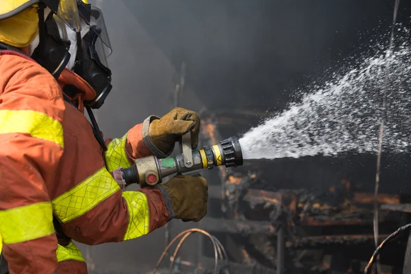 2 bomberos rociando agua en la operación de extinción de incendios —  Fotos de Stock