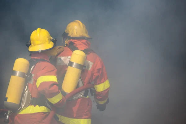 Dos bomberos trabajan rodeados de humo y polvo —  Fotos de Stock