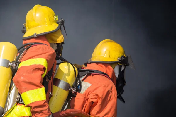 2 bombeiros em operação e fundo de fumaça escura — Fotografia de Stock