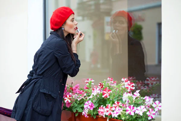 Ein Mädchen mit roter Baskenmütze geht bei trübem Wetter durch eine Stadt — Stockfoto