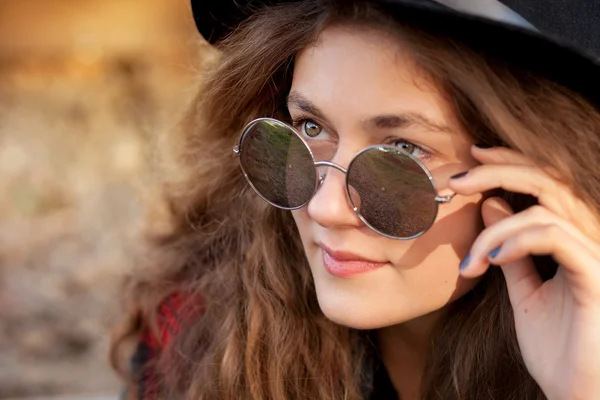 Una chica se sienta sobre rieles en el soleado clima otoñal — Foto de Stock