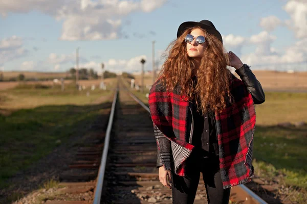 Chica en un sombrero caminando a lo largo del ferrocarril en el sol de otoño — Foto de Stock