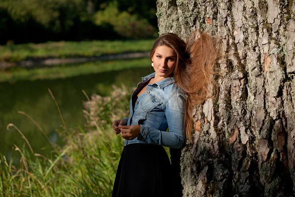 Muchacha joven con el pelo largo en un lago en tiempo soleado — Foto de Stock