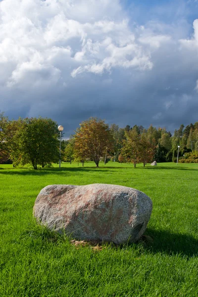 Vertikale Aufnahme eines Parks mit Stein im Vordergrund und dramatischem Clou — Stockfoto