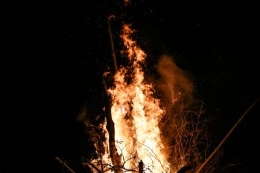 Yerde yakacak odunları olan ateş. Kırmızı alevler. Güzel kıvılcımlar saçan siyah arka plan..