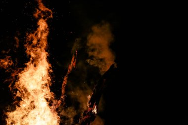 Yerde yakacak odunları olan ateş. Kırmızı alevler. Güzel kıvılcımlar saçan siyah arka plan..