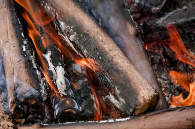 Yerde yakacak odunları olan ateş. Kırmızı alevler. Güzel kıvılcımlar saçan siyah arka plan..