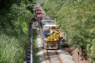 Kentte demir cevheri dolu konteynırlarla hareket eden Bayan S yük treninin görüntüsü.