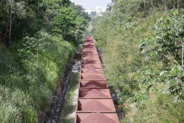 Kentte demir cevheri dolu konteynırlarla hareket eden Bayan S yük treninin görüntüsü.