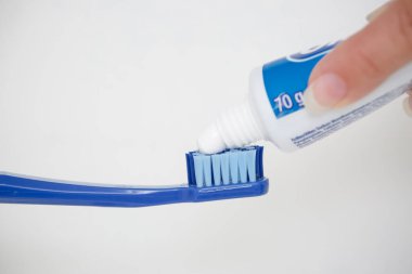 Büyük mavi bir diş fırçasına diş macunu sürüyorum..