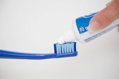 Büyük mavi bir diş fırçasına diş macunu sürüyorum..