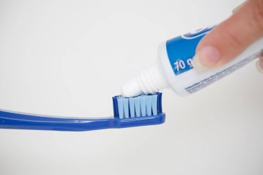 Büyük mavi bir diş fırçasına diş macunu sürüyorum..