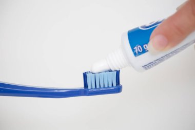 Büyük mavi bir diş fırçasına diş macunu sürüyorum..