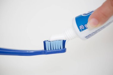 Büyük mavi bir diş fırçasına diş macunu sürüyorum..