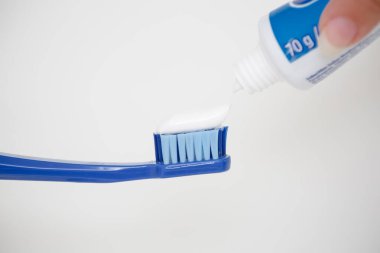 Büyük mavi bir diş fırçasına diş macunu sürüyorum..