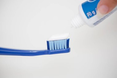 Büyük mavi bir diş fırçasına diş macunu sürüyorum..