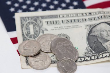 Altında bozuk para ve bayrak olan 1 dolarlık ABD banknotu..
