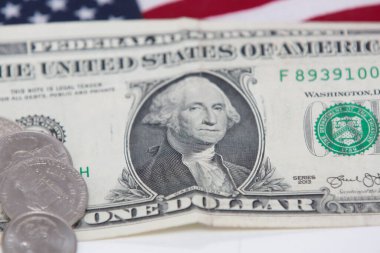 Altında bozuk para ve bayrak olan 1 dolarlık ABD banknotu..