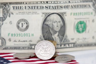 Altında bozuk para ve bayrak olan 1 dolarlık ABD banknotu..