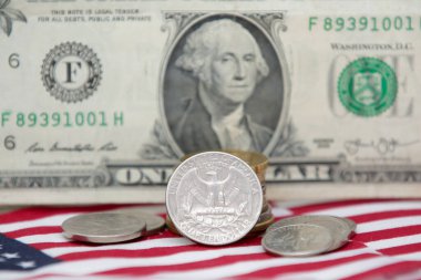 Altında bozuk para ve bayrak olan 1 dolarlık ABD banknotu..
