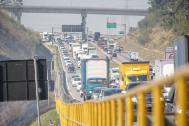 Dutra otoyolunun yanındaki yangın trafiği yavaşlatıyor, itfaiyeciler yangını söndürüyor..
