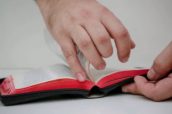 Holy Bible open in hand and being flipped through by people.