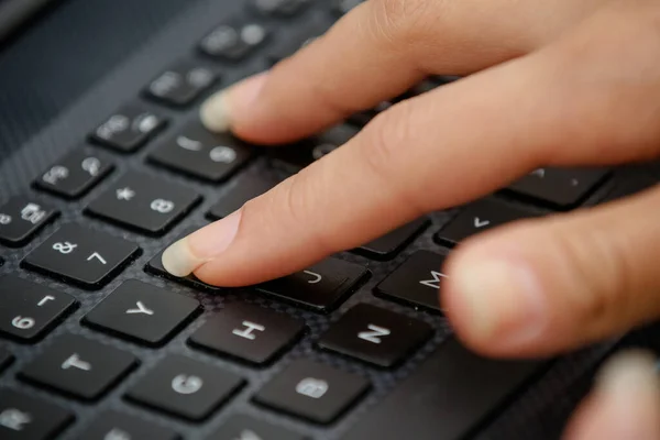 hand on the black keyboard of a computer typing text.