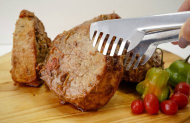 Tahtada bıçak ve çatal bıçakla pişirilmiş et dilimi..