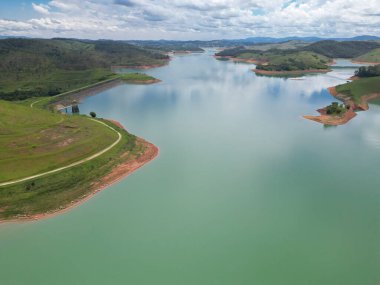 Doğayla çevrili, gökyüzünü ve çevrenin huzurunu yansıtan huzurlu bir baraj manzarası. Sahne, bir yaşam kaynağı olarak sakin, dengeli, sürdürülebilirlik ve suyla bağlantıyı iletir..