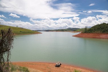 Doğayla çevrili, gökyüzünü ve çevrenin huzurunu yansıtan huzurlu bir baraj manzarası. Sahne, bir yaşam kaynağı olarak sakin, dengeli, sürdürülebilirlik ve suyla bağlantıyı iletir..