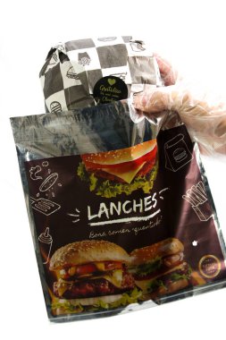 Hamburger teslimatı için termal paket tek kullanımlık eldivenle tutuluyor. Paket yemek, fast food, hijyen, gıda güvenliği ve modern dağıtım hizmeti kavramı.