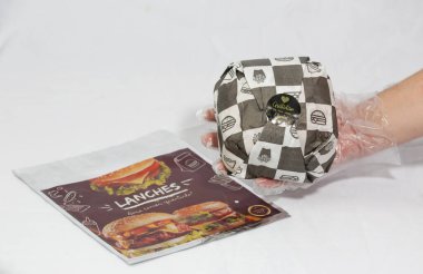 Hamburger teslimatı için termal paket tek kullanımlık eldivenle tutuluyor. Paket yemek, fast food, hijyen, gıda güvenliği ve modern dağıtım hizmeti kavramı.