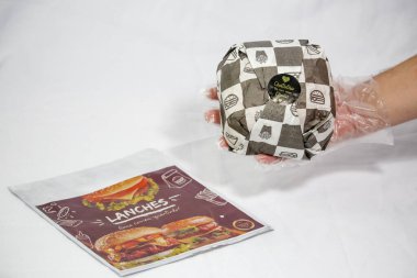 Hamburger teslimatı için termal paket tek kullanımlık eldivenle tutuluyor. Paket yemek, fast food, hijyen, gıda güvenliği ve modern dağıtım hizmeti kavramı.