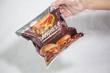 Hamburger teslimatı için termal paket tek kullanımlık eldivenle tutuluyor. Paket yemek, fast food, hijyen, gıda güvenliği ve modern dağıtım hizmeti kavramı.